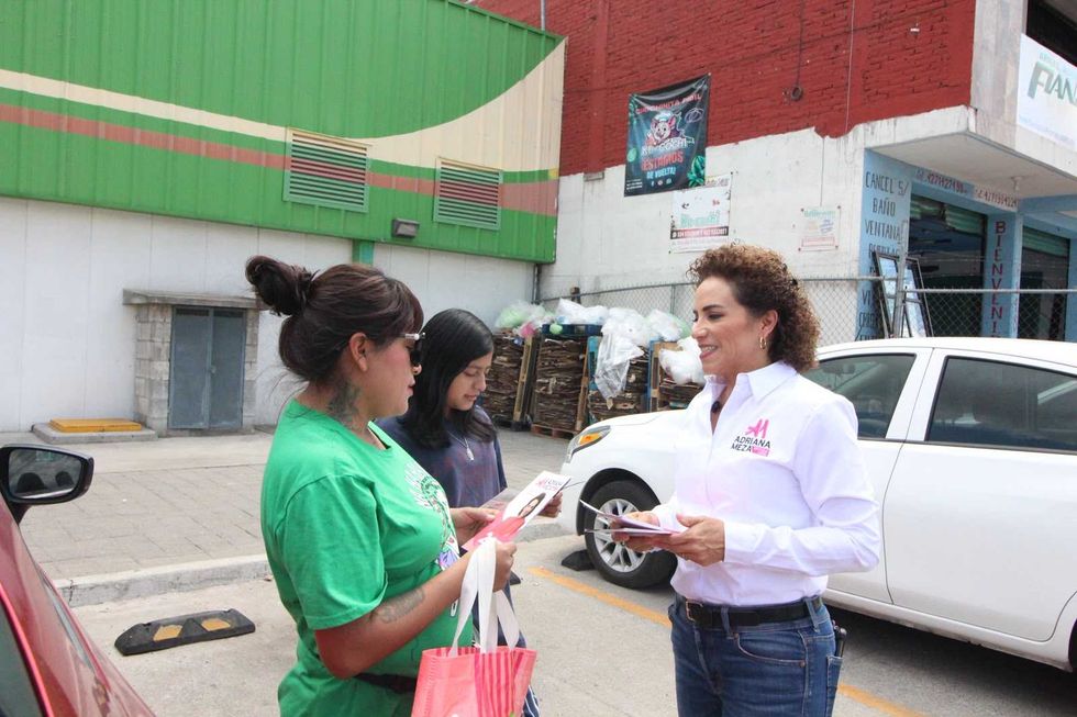 Adriana Meza revisa folletos con dos hombres durante su informe legislativo en San Juan del R\u00edo