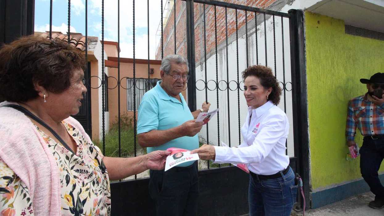 Adriana Meza revisa folletos con dos hombres durante su informe legislativo en San Juan del Río