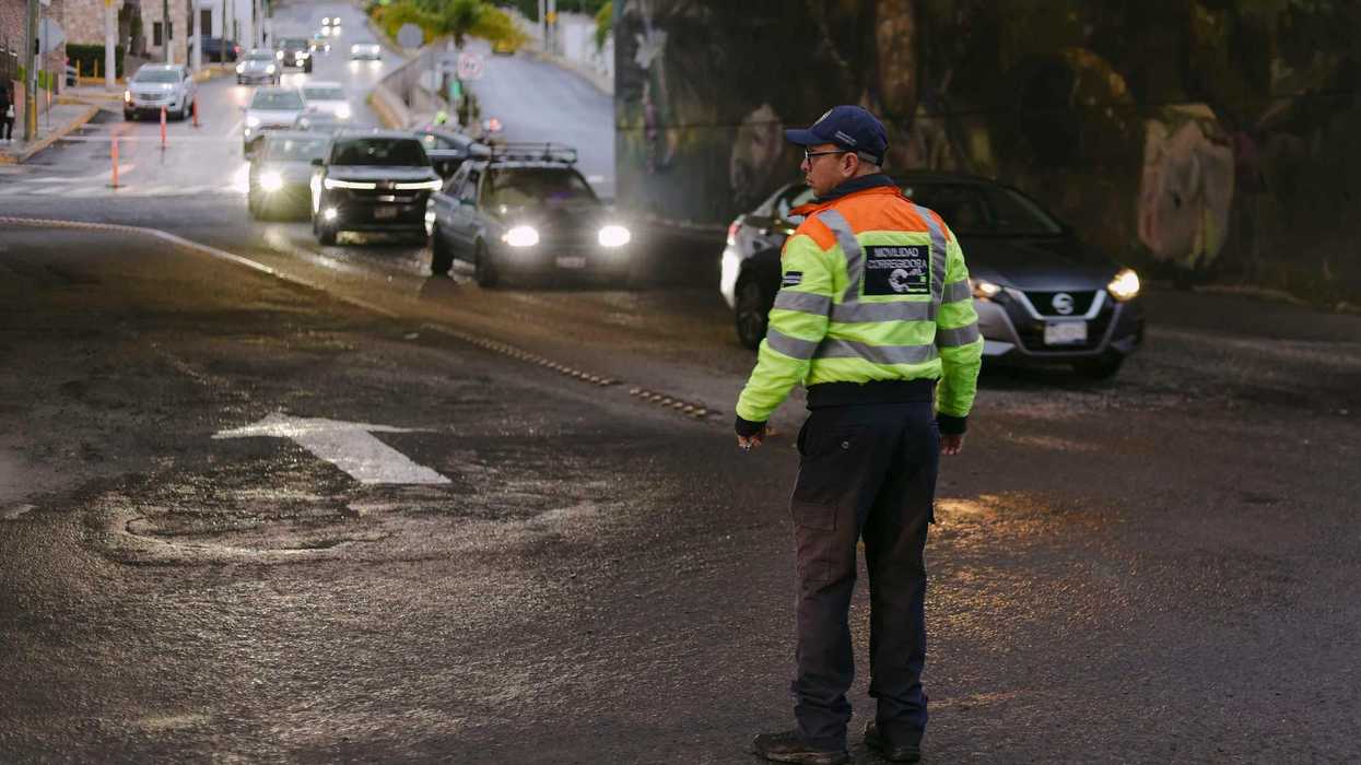 Agente de Movilidad de Corregidora, de espaldas, indica el paso a un automóvil blanco durante el operativo vial