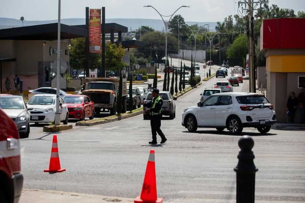Agente de Tr\u00e1nsito Vial da paso a peatones en un crucero de San Juan del R\u00edo durante el operativo de D\u00eda de Muertos