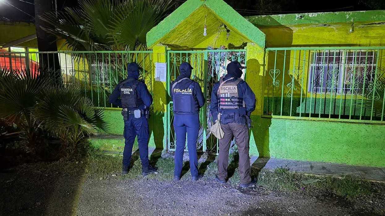 Agentes de la Fiscalía de Michoacán y de la Guardia Civil ante el portón de una vivienda durante cateos en Copándaro