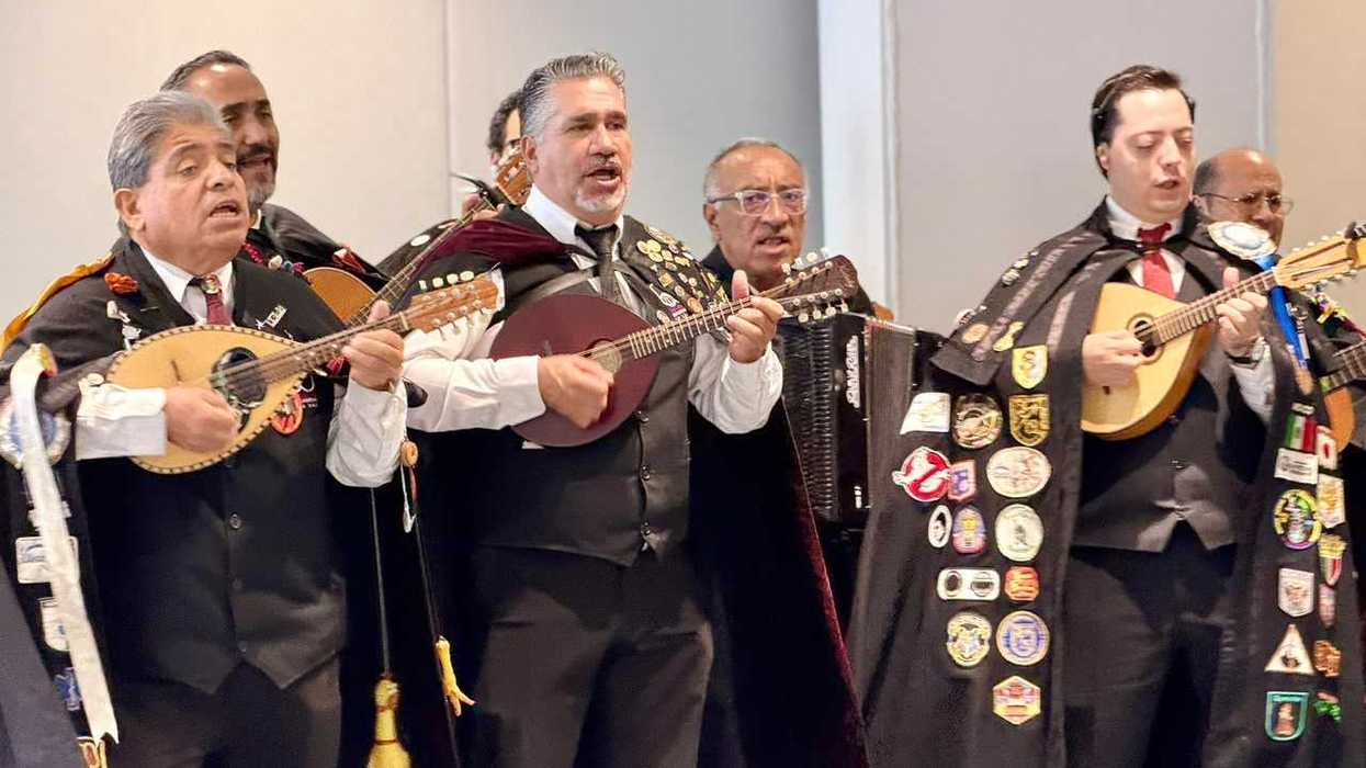 Agrupación con capas interpreta piezas con instrumentos de cuerda y acordeón durante una presentación artística