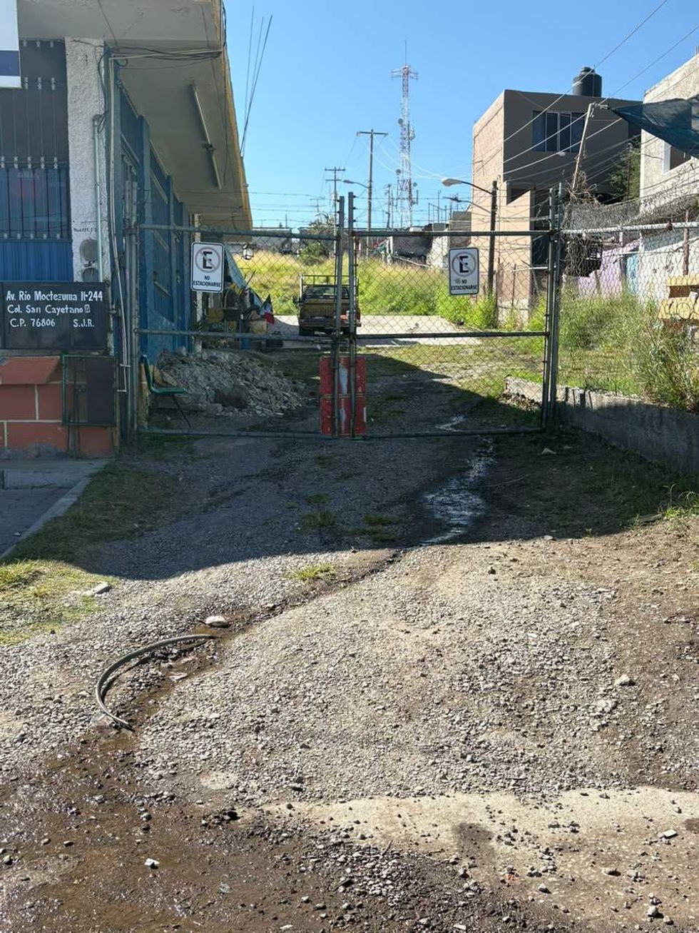 Agua acumulada sobre un piso de concreto detr\u00e1s de una malla cicl\u00f3nica en la zona de la fuga de avenida R\u00edo Moctezuma, San Juan del R\u00edo.