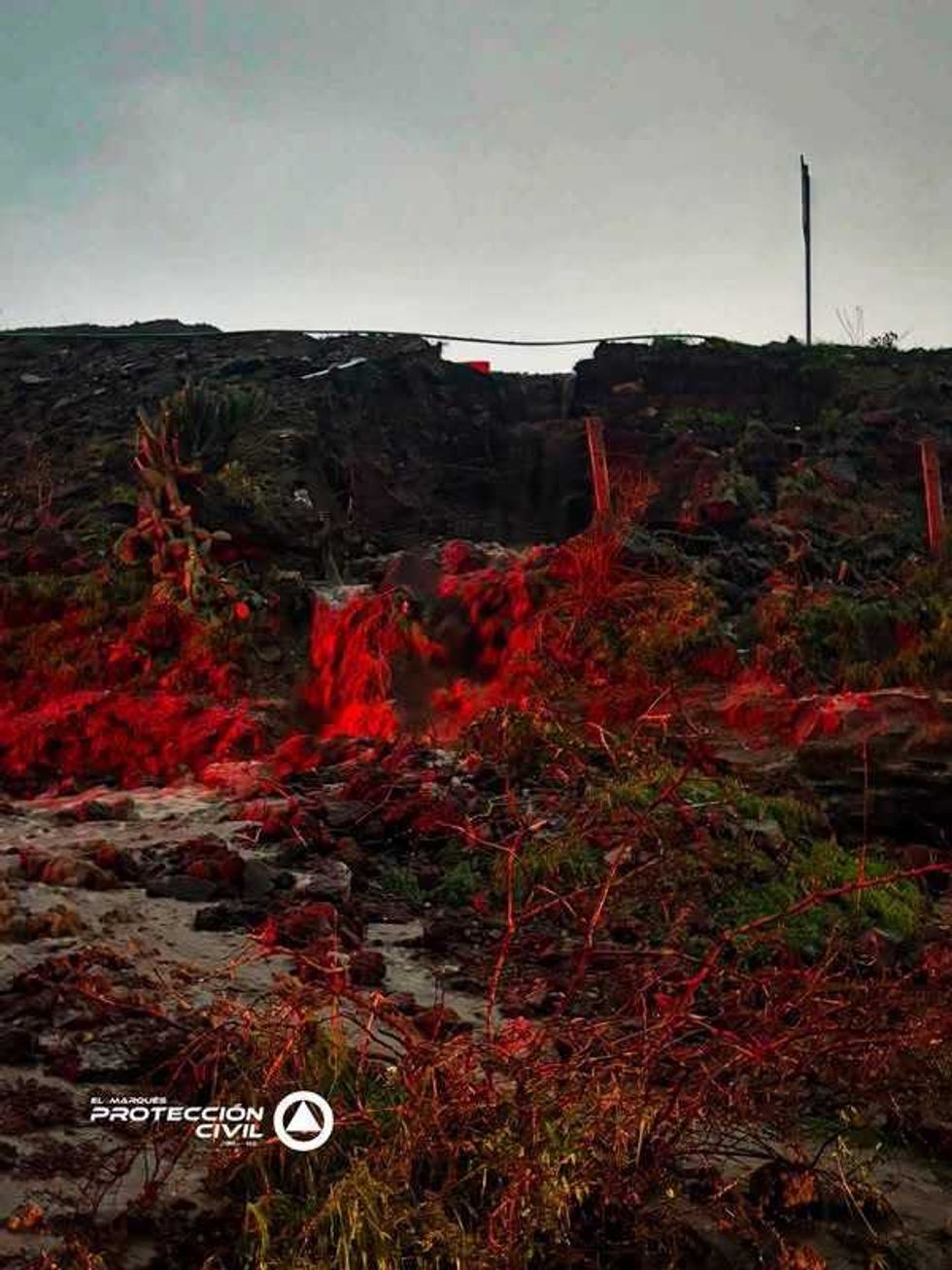 Agua y escombros descienden por el talud de la zona de obras en la antigua Cuesta China, El Marqu\u00e9s, iluminados por luz roja de emergencia