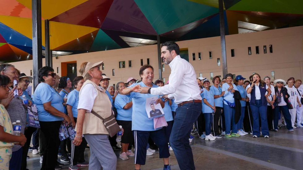 Agust\u00edn Dorantes L\u00e1mbarri y un funcionario estatal entregan volantes del Quinto Informe de Gobierno a comerciantes del mercado del Tepetate en Quer\u00e9taro.