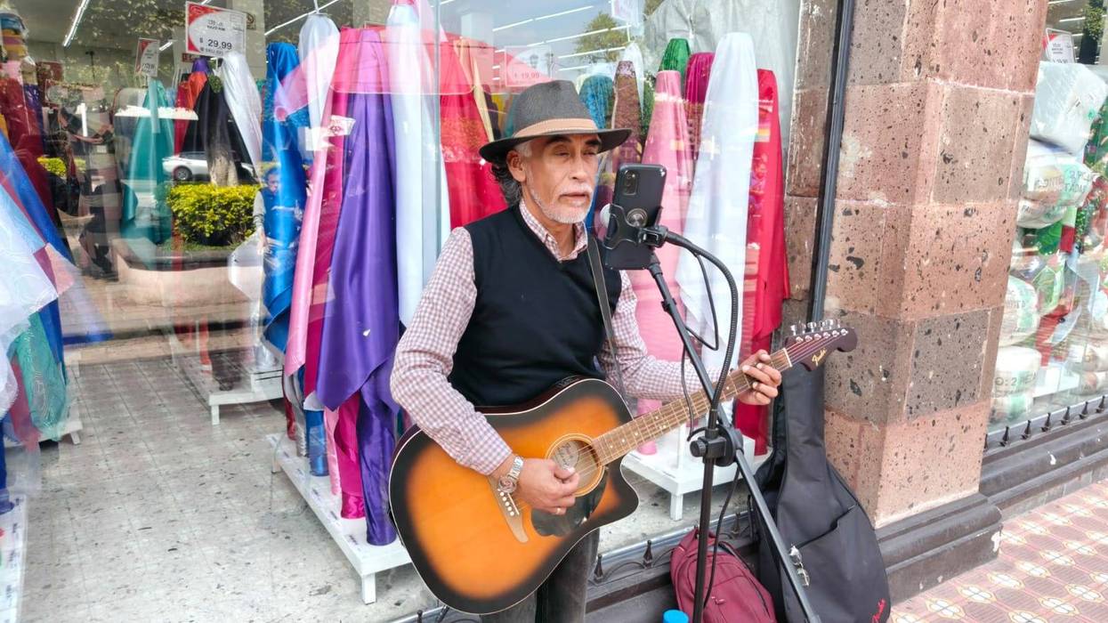 Alberto Sandoval Almanza toca guitarra como músico callejero en el Jardín de la Familia de San Juan del Río.
