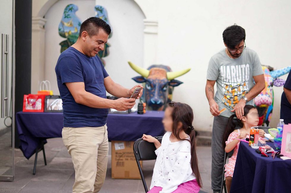ALT: Un pap\u00e1 fotograf\u00eda a su hija durante el taller Manos de Pap\u00e1 en Corregidora.
