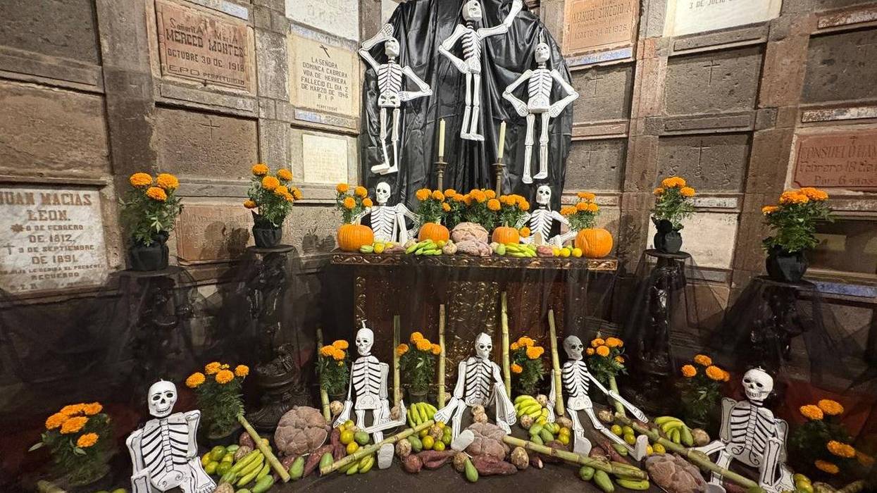 Altar de muertos con figuras de esqueletos, cempasúchil, pan y fruta ante nichos del Museo de la Muerte de San Juan del Río