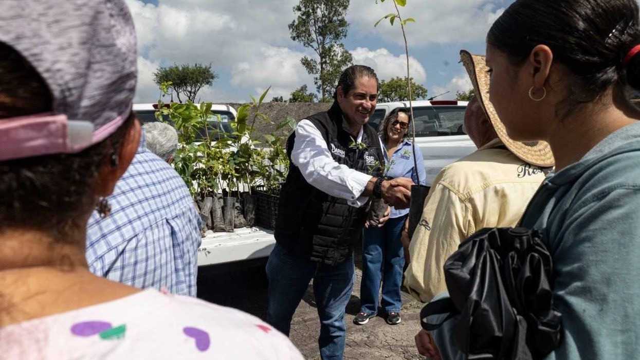 Antonio Pérez Cabrera entrega una planta a una habitante durante la jornada del bordo El Cajete en Puerta de Palmillas