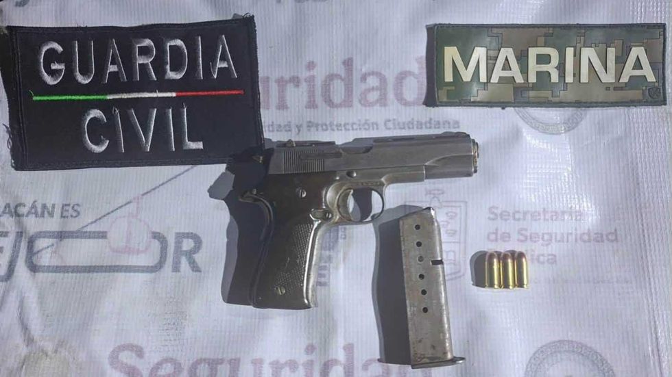 Arma de fuego, cargador y cartuchos asegurados por autoridades en L\u00e1zaro C\u00e1rdenas, Michoac\u00e1n, junto a parches de Guardia Civil y Marina