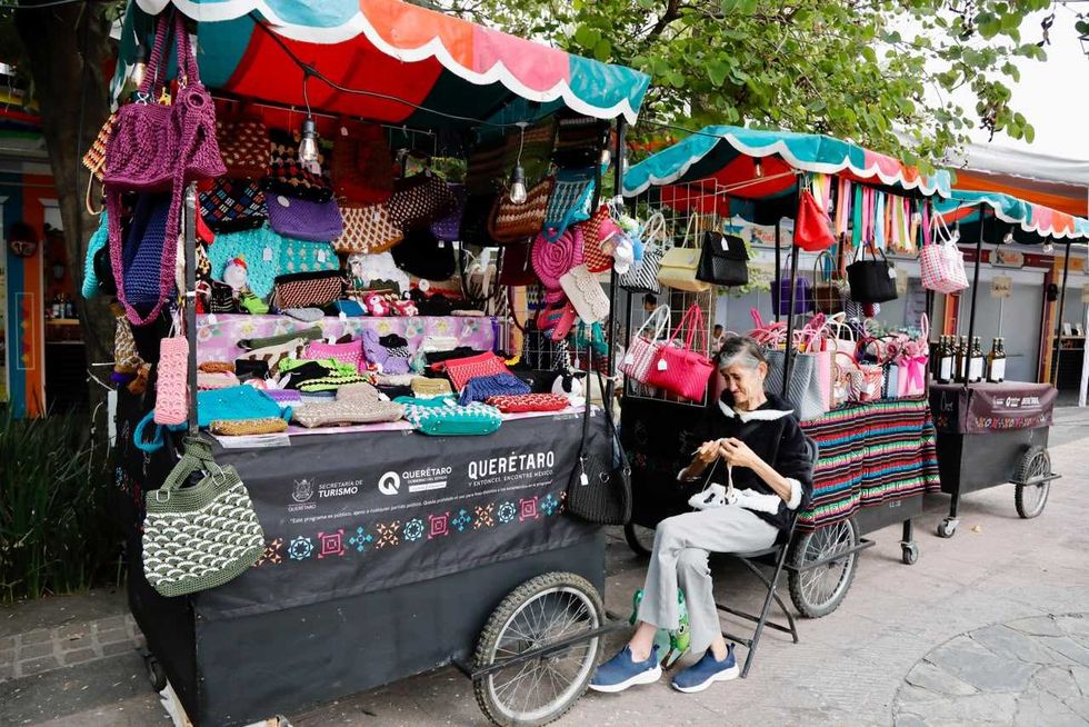 Artesana teje junto a carritos con bolsas y tejidos en el Festival X\u00f6nthe, Col\u00f3n, Quer\u00e9taro 2026