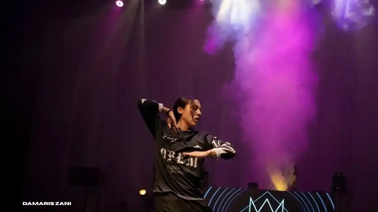 Artista de danza urbana durante una presentación escénica de CEOYEN en Querétaro, con iluminación violeta y efectos de humo.