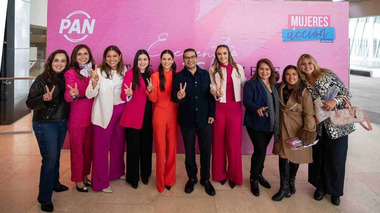 Asistentes al Encuentro Estatal de Mujeres del PAN ondean banderas del partido en un auditorio de Querétaro