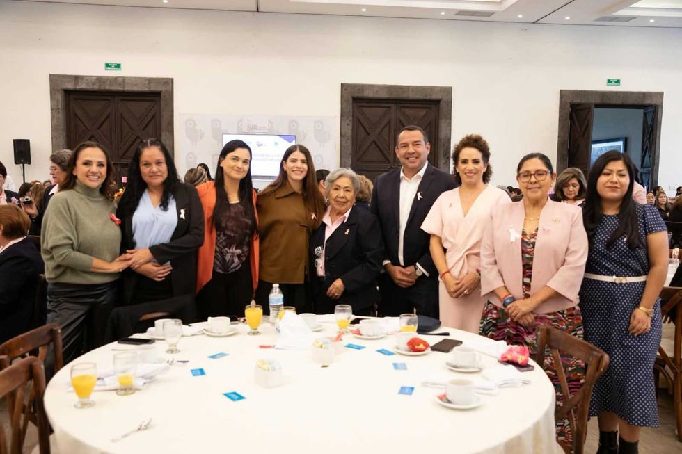 Asistentes al XXIII Desayuno Anual de Grupo Reto posan alrededor de una mesa redonda con arreglo floral en San Juan del R\u00edo