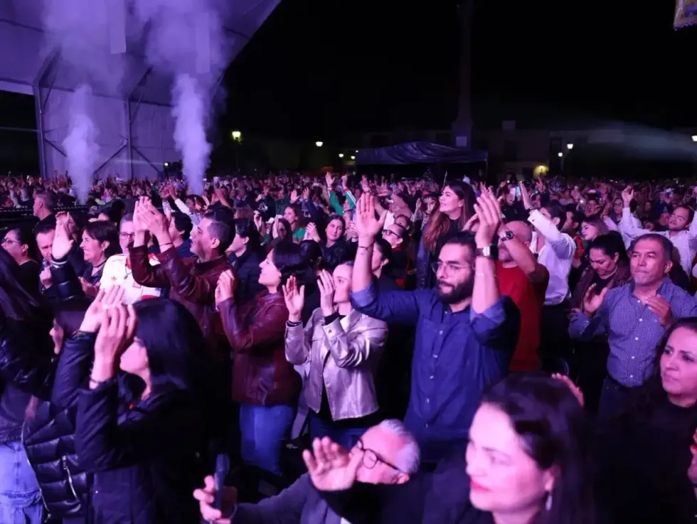 Asistentes aplauden y levantan las manos durante el concierto de clausura en el Jard\u00edn Independencia