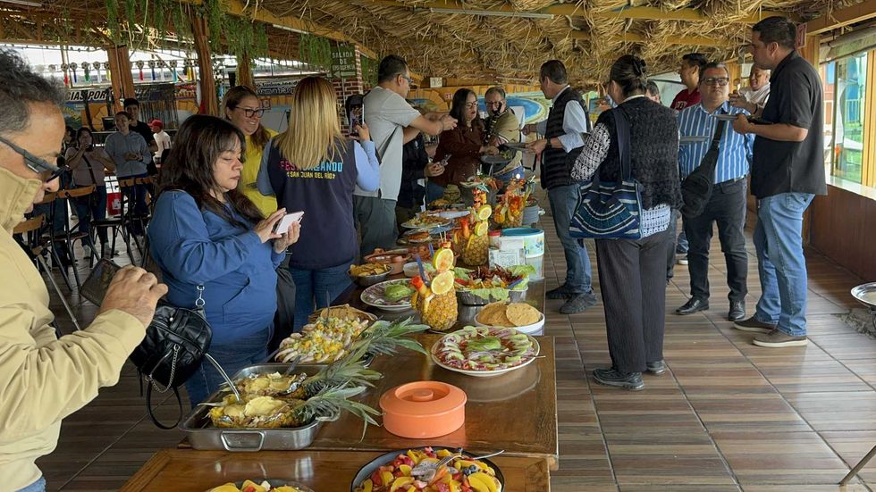 Asistentes fotograf\u00edan una mesa con platillos de mariscos durante la presentaci\u00f3n del festival