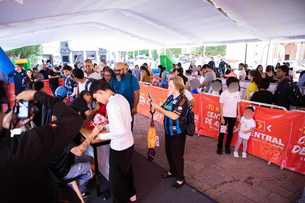 Asistentes hacen fila bajo una carpa en el Jard\u00edn Independencia de San Juan del R\u00edo durante la firma de aut\u00f3grafos de Gallos Blancos.