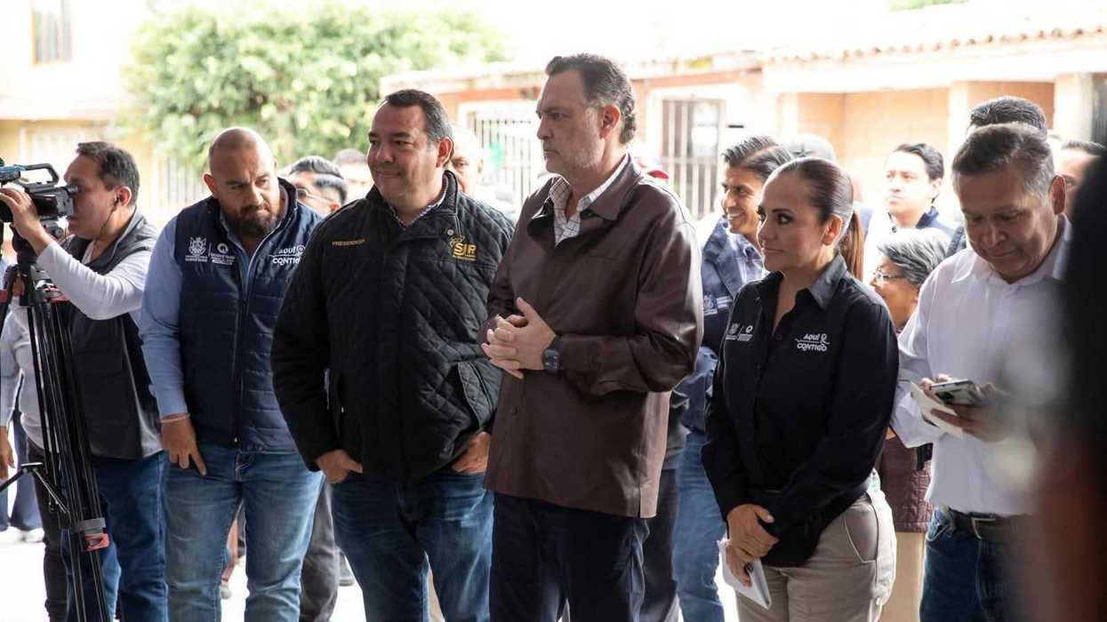Asistentes y camarógrafos escuchan un mensaje bajo una carpa en la entrega de obra en Infonavit San Isidro, San Juan del Río