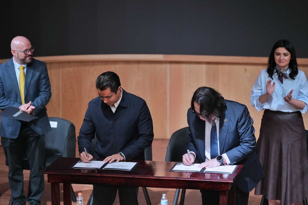 Asistentes y firmantes posan con los convenios del Laboratorio de Innovaci\u00f3n en Procuraci\u00f3n de Justicia en un auditorio