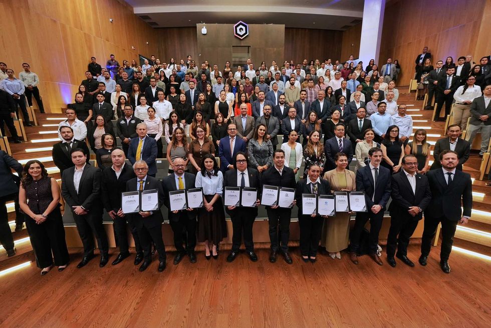 Asistentes y firmantes posan con los convenios del Laboratorio de Innovaci\u00f3n en Procuraci\u00f3n de Justicia en un auditorio