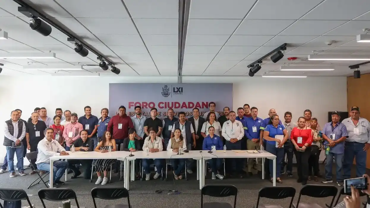 Asistentes y presídium posan en foro ciudadano sobre la reforma a la Ley de Servicios Auxiliares, frente a un banner institucional, en Querétaro.