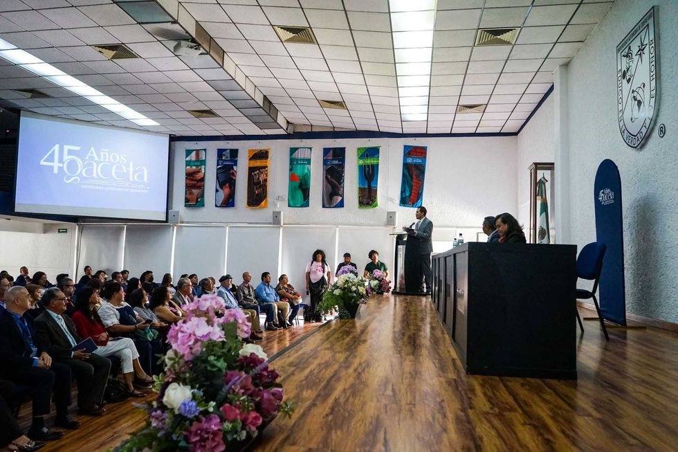 Auditorio de la UAQ durante la ceremonia por los 45 a\u00f1os de la Gaceta Universitaria, con p\u00fablico y un orador en el estrado.