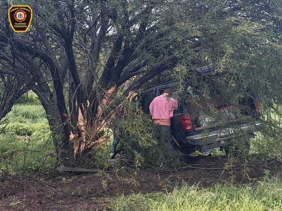 Autom\u00f3vil sed\u00e1n de color claro fuera de la vialidad, sobre una zona con vegetaci\u00f3n junto a un canal, a la altura de la carretera 200.