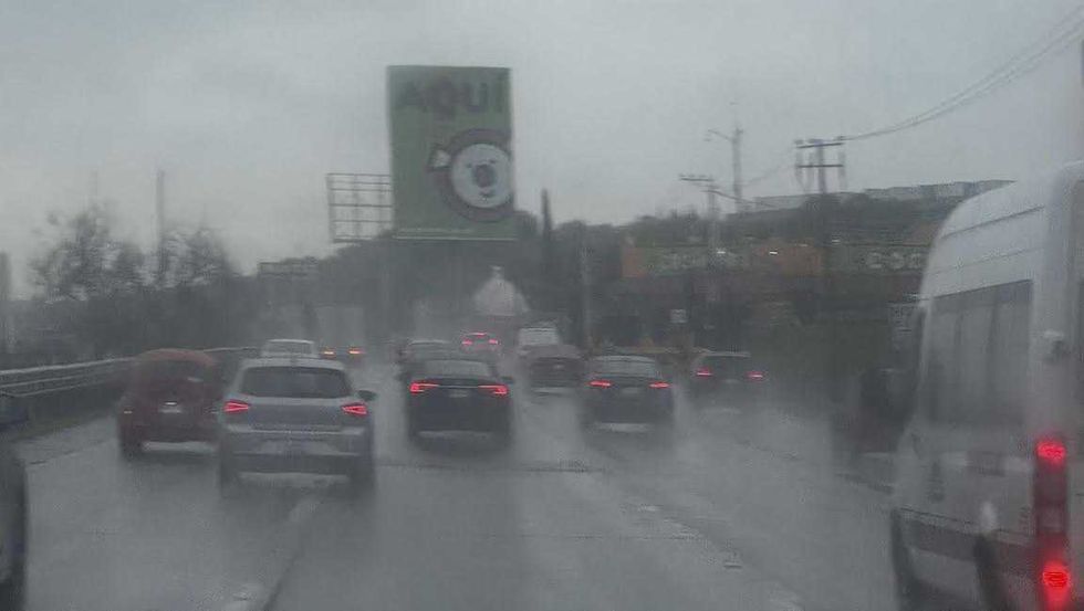 Autom\u00f3viles avanzan lentamente sobre una avenida con agua acumulada bajo cielo nublado en Quer\u00e9taro.