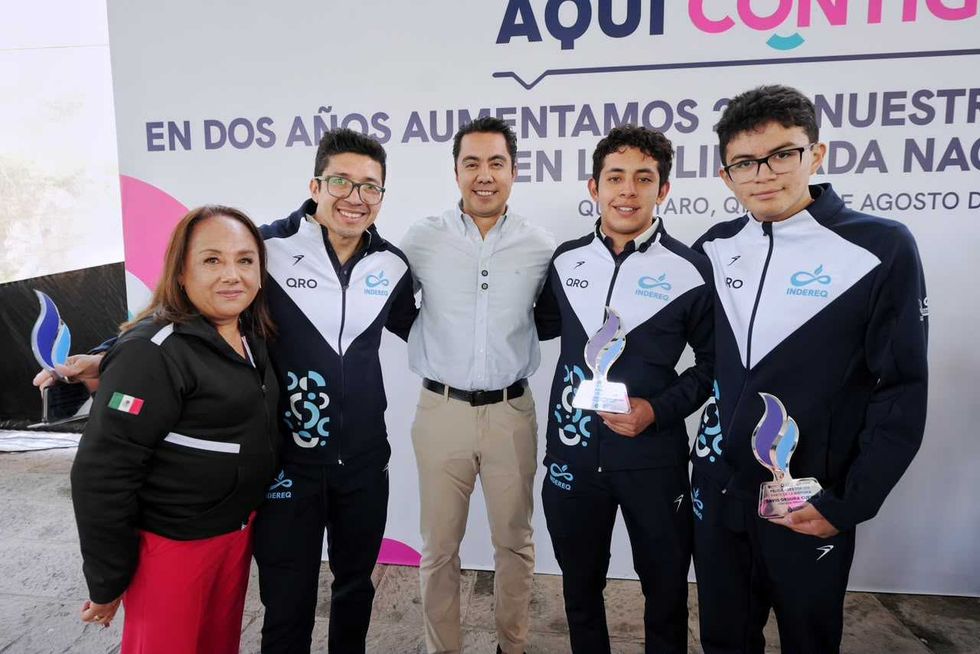 Autoridades de Quer\u00e9taro posan junto a deportistas que sostienen reconocimientos por sus resultados deportivos.