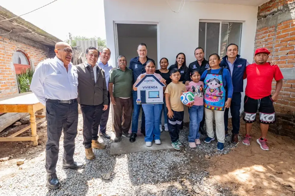 Autoridades estatales y la familia beneficiaria muestran el certificado de vivienda en Santa Cruz Escand\u00f3n