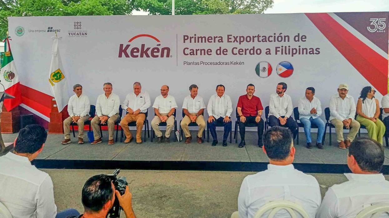 Autoridades sentadas en fila ante una manta sobre la primera exportación de carne de cerdo a Filipinas