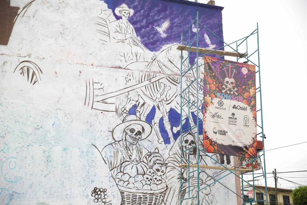 Boceto de calaveras y una carreta en el Mural de las \u00c1nimas de San Juan del R\u00edo, junto a un andamio