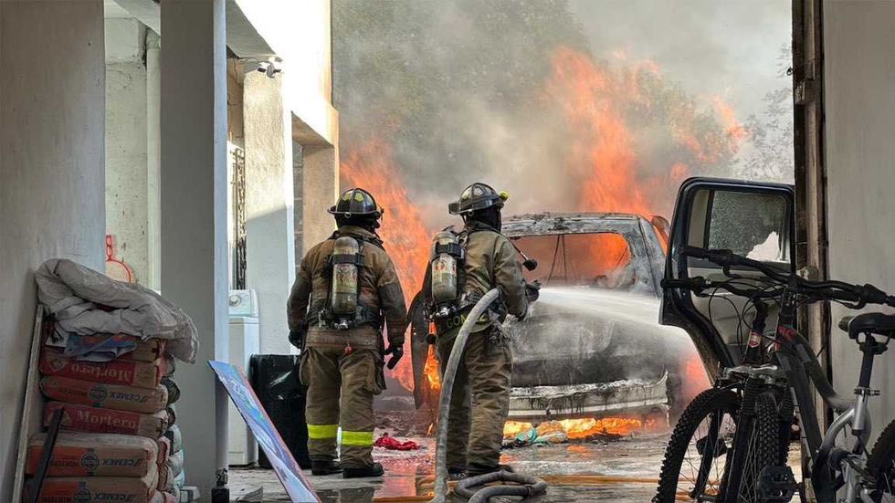 Bomberos de San Juan del R\u00edo controlan el fuego junto a dos veh\u00edculos calcinados en el patio de un domicilio.