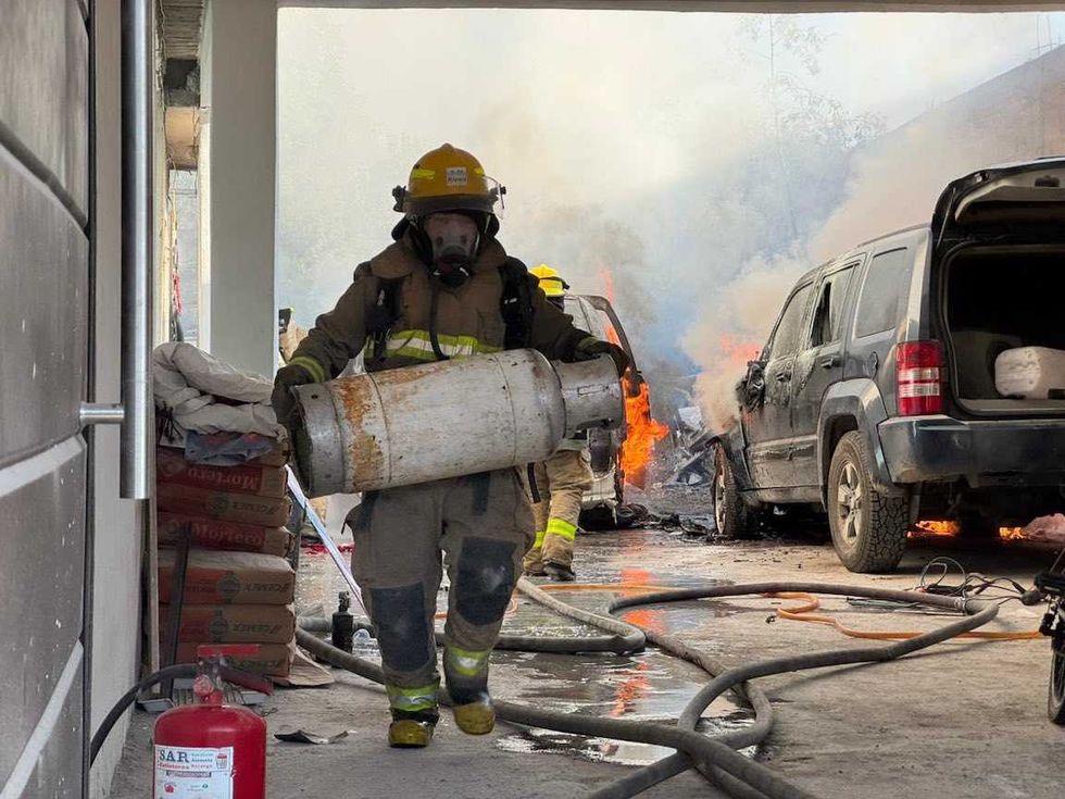 Bomberos de San Juan del R\u00edo controlan el fuego junto a dos veh\u00edculos calcinados en el patio de un domicilio.