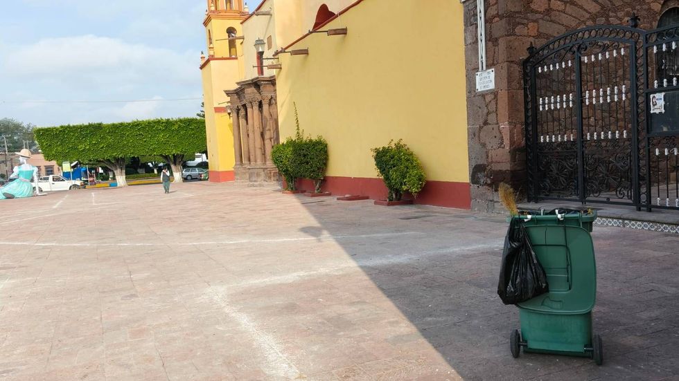 Bote de basura verde con escoba frente a un templo amarillo en la zona centro de San Juan del R\u00edo donde laboran barrenderos