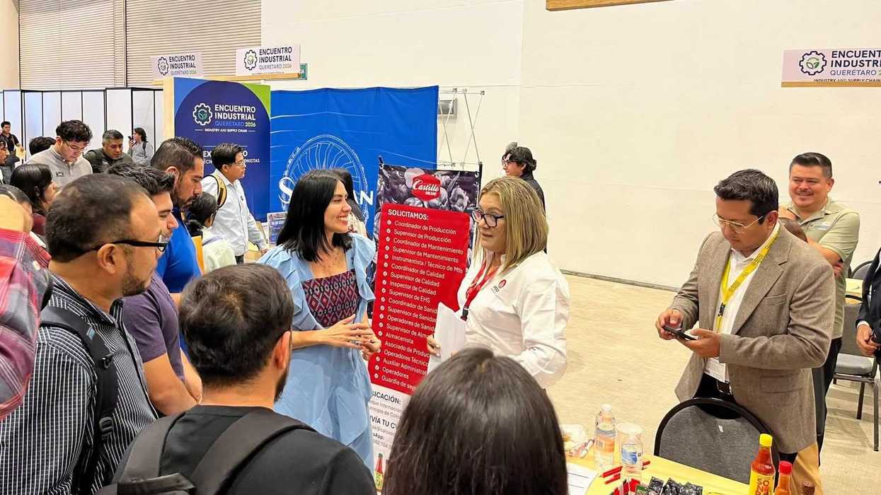 Buscadores de empleo conversan con reclutadoras frente a un stand con lista de vacantes durante el Encuentro Industrial Querétaro 2026.