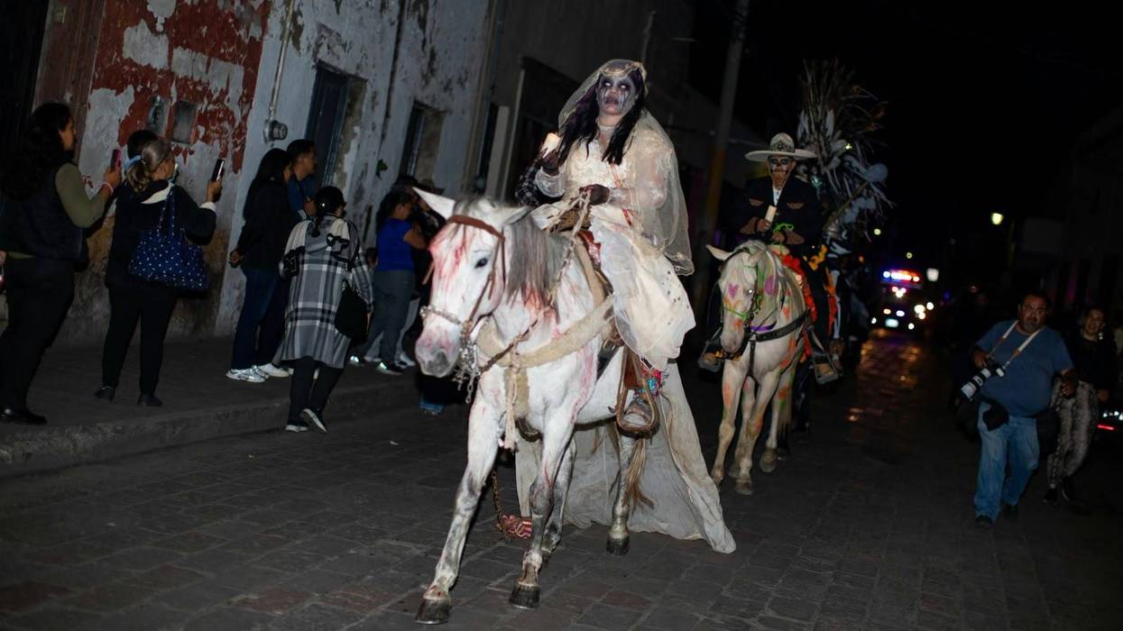 Cabalgata de los Muertos: jinete caracterizada de Catrina en caballo adornado, seguida por jinetes con velas