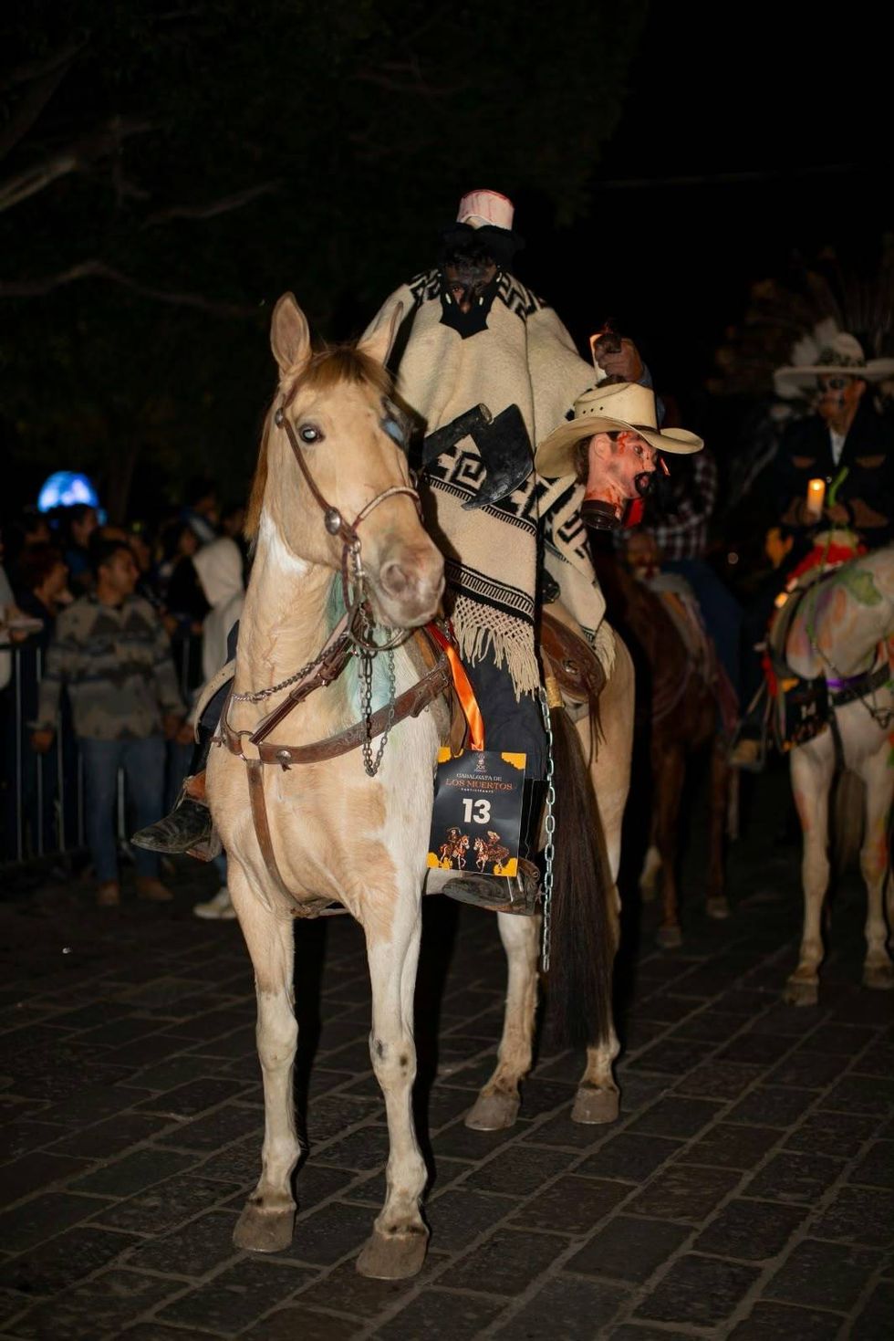 Cabalgata de los Muertos: jinete caracterizado como personaje sin cabeza, con n\u00famero de participante, en caballo palomino