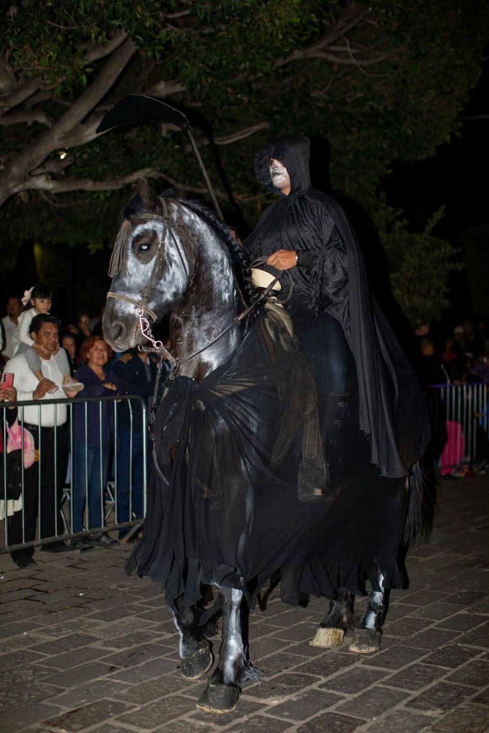 Cabalgata de los Muertos: jinete con sombrero negro, rostro de calavera y capa guinda sobre caballo caf\u00e9
