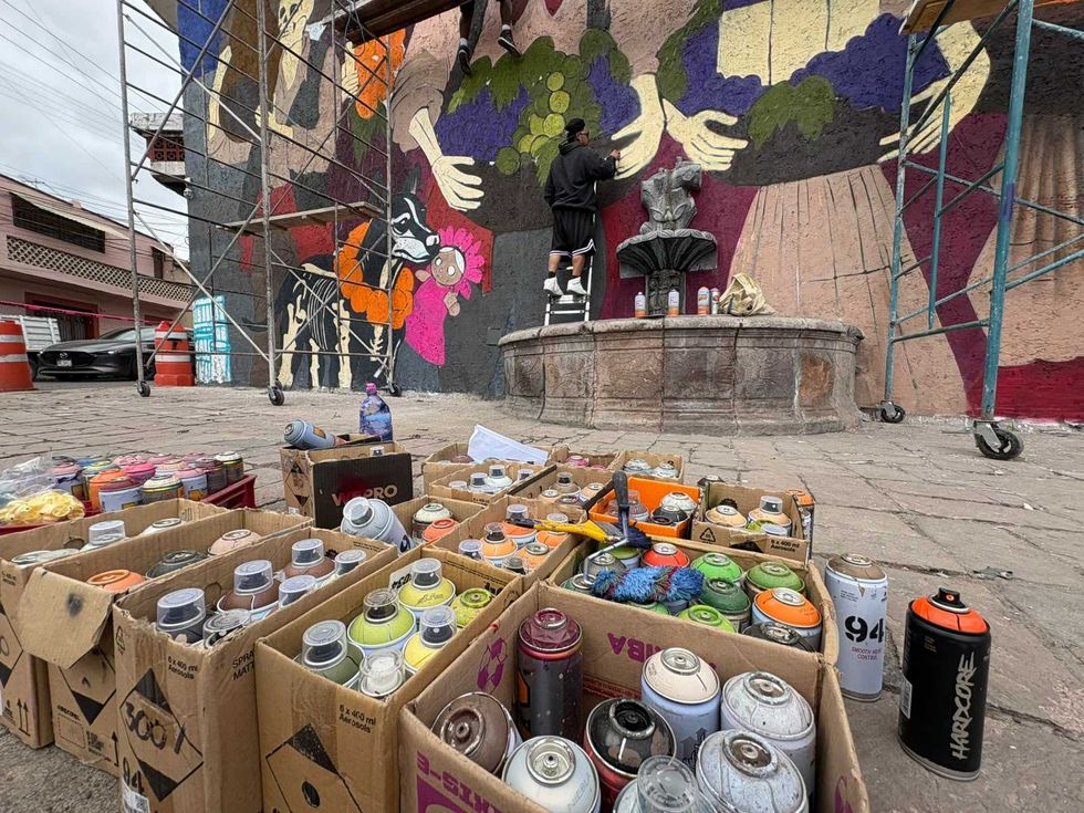 Cajas con botes de aerosol frente al mural y la fuente de la calle Hidalgo