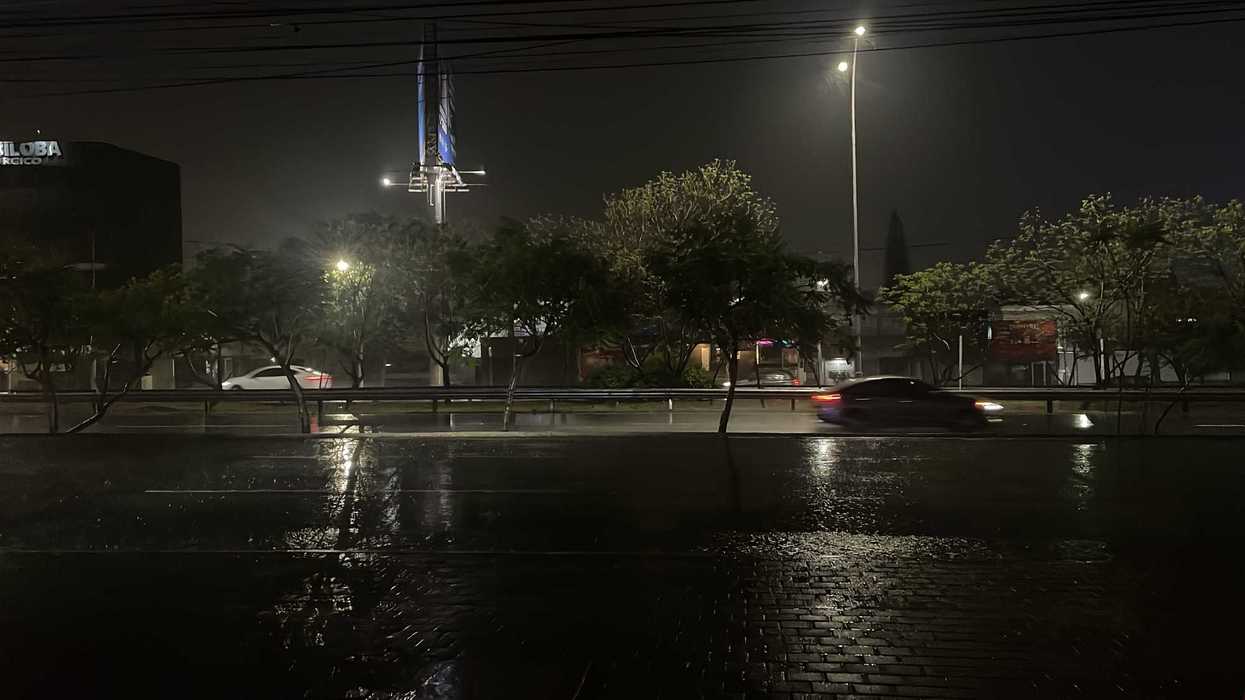 Calle de la capital de Querétaro cubierta de agua tras la lluvia, con un vehículo detenido entre la corriente acumulada.
