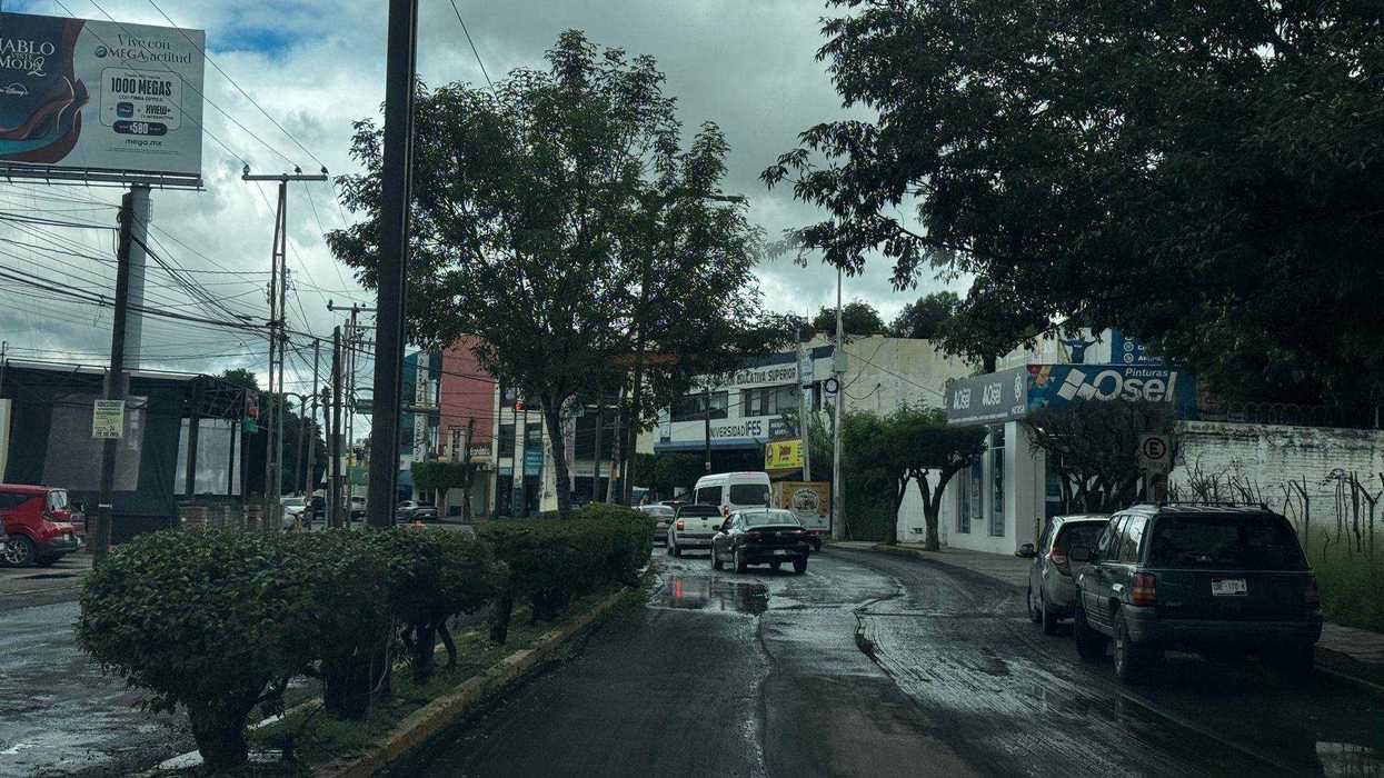 Calle encharcada de San Juan del Río donde la lluvia detuvo la aplicación de asfalto en la obra vial estatal