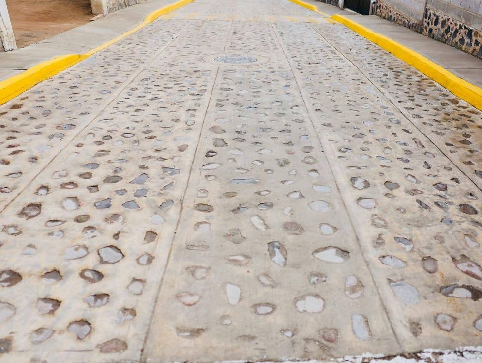 Calle Miguel Hidalgo con empedrado h\u00famedo y guarniciones amarillas rehabilitada en Santa B\u00e1rbara La Cueva