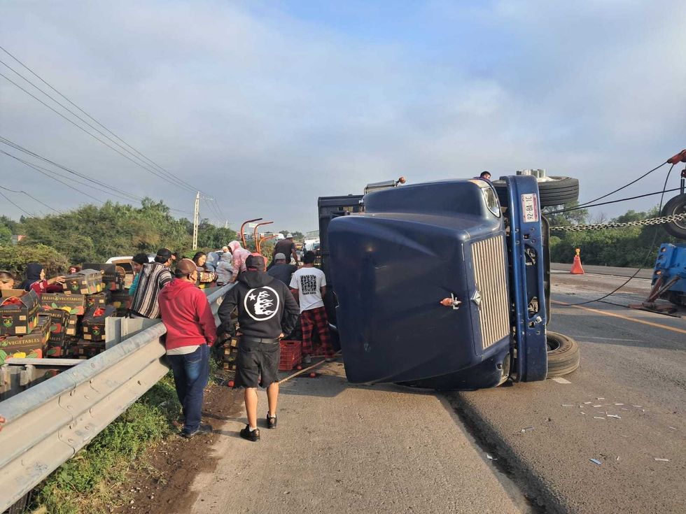 Cami\u00f3n de carga volcado y personas junto a cajas de jitomate en la autopista M\u00e9xico-Quer\u00e9taro.