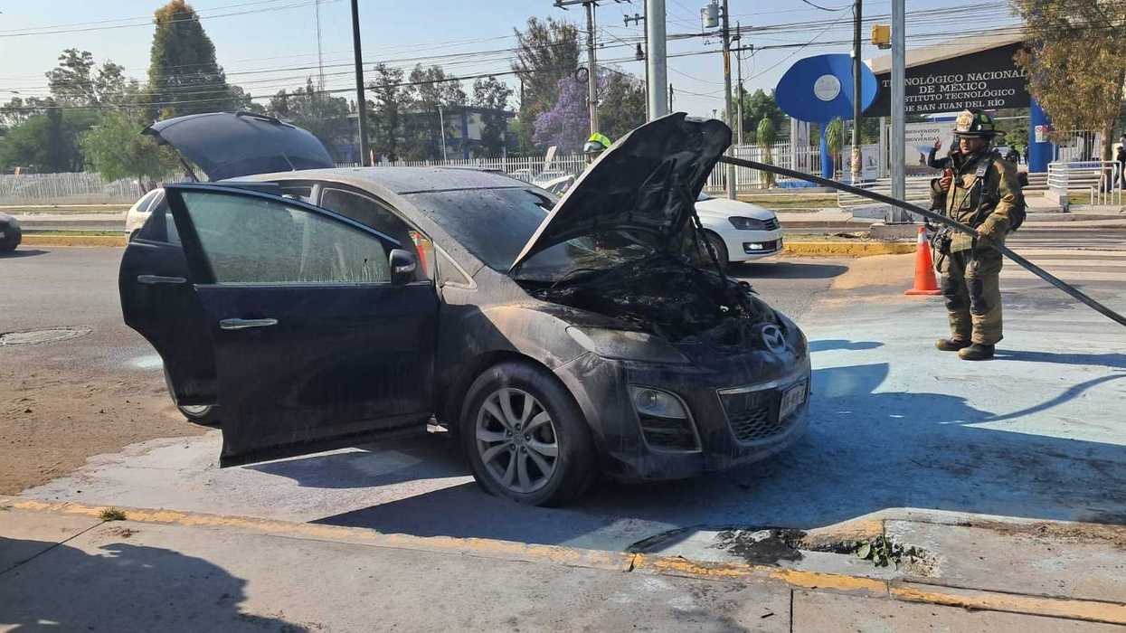 Camioneta Mazda gris incendiada sobre Avenida Tecnológico en San Juan del Río, con presencia de bomberos en el lugar