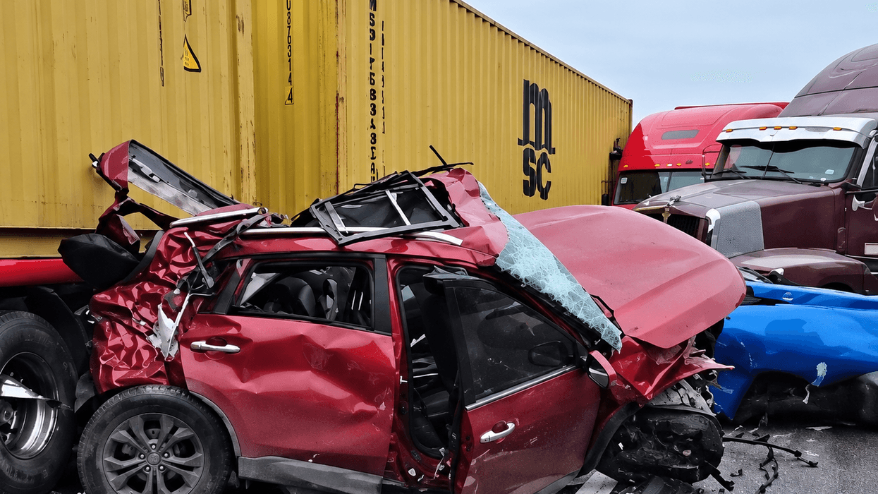 Camioneta roja destrozada contra el contenedor de un tractocamión, con otros tractocamiones al fondo, en una imagen ilustrativa de la carambola en la autopista México-Querétaro.