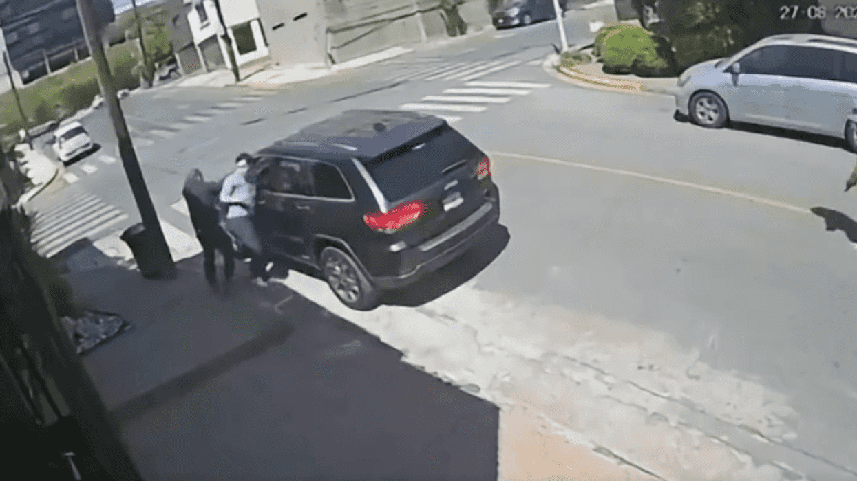 Captura de video de vigilancia muestra a un hombre armado sometiendo a la víctima junto a una camioneta en la vía pública en San Pedro, Nuevo León