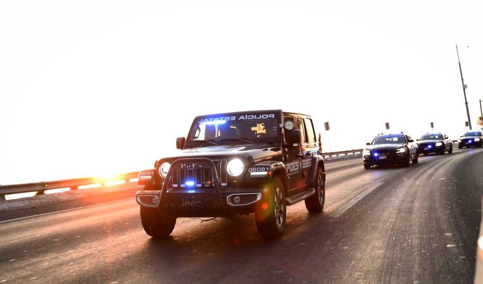 Caravana de patrullas de la Polic\u00eda Estatal de Quer\u00e9taro con torretas encendidas circula por una autopista al atardecer.