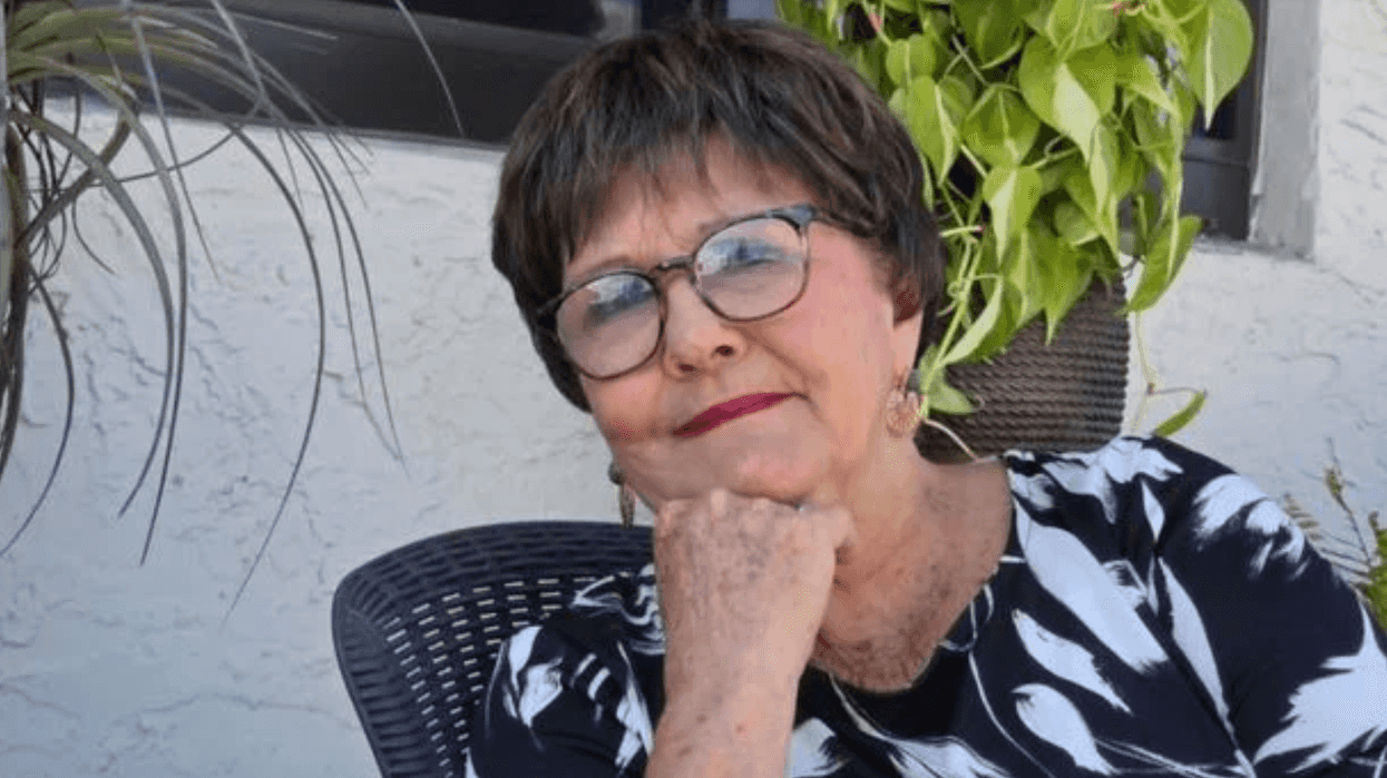 Carolina Luz de la Torre Molina, psicóloga cubana conocida como la “profe Carola”, con anteojos y la mano bajo el mentón, sentada junto a plantas.
