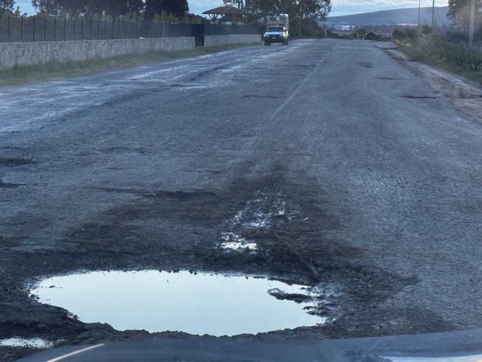 Carretera de Nopala de Villagr\u00e1n con dos baches profundos llenos de agua y pavimento roto durante la temporada de lluvias.